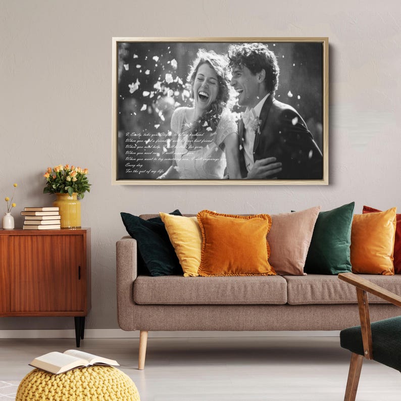 May include: A rectangular black and white canvas print in a gold frame featuring a laughing couple surrounded by falling petals. The image includes white cursive text overlaid on the left side, depicting a wedding scene with a person in a dress.
