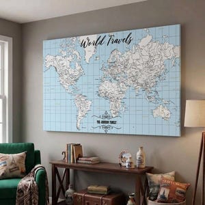 May include: A rectangular wall art canvas featuring a light blue world map with a grid overlay. The text World Travels is printed in black script at the top, and the text The Joerson Family is centred at the bottom with decorative flourishes.