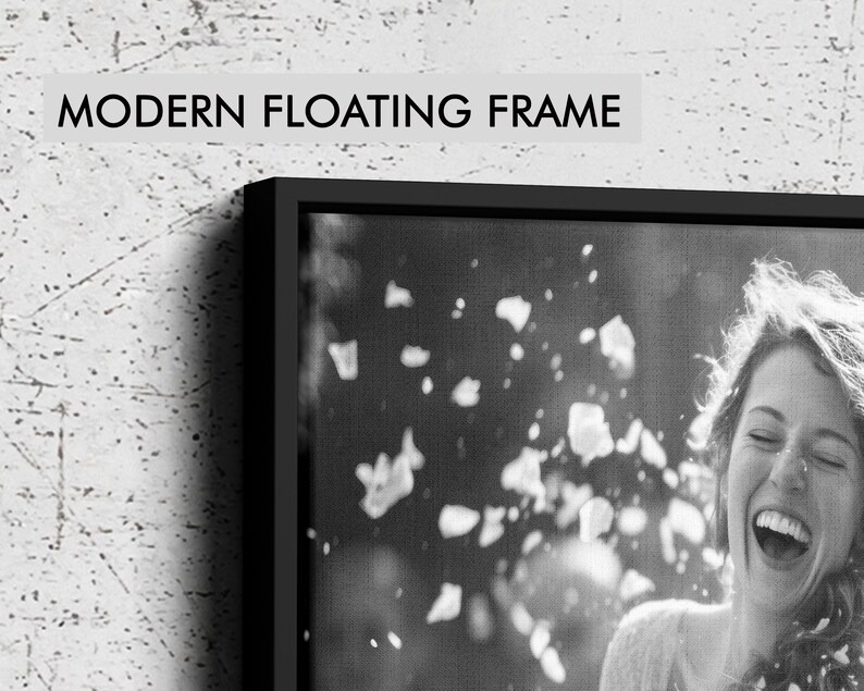 May include: A black floating frame containing a black and white photograph of a laughing person with falling petals. The text MODERN FLOATING FRAME is printed in black on a light gray background above the frame, which has a thin black border.