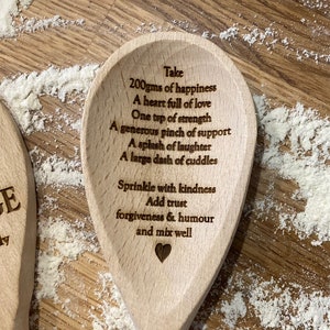 Wooden  spoon with a recipe for happiness engraved on it. The recipe includes 200 grams of happiness, a heart full of love, one teaspoon of strength, a generous pinch of support, a splash of laughter, a large dash of cuddles, a sprinkle of kindness, trust, forgiveness and humour, and to mix well.