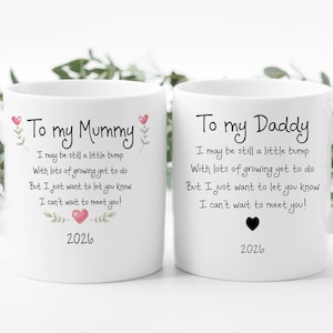 May include: Two white ceramic mugs featuring black printed text. The left mug reads To my Mummy with a poem and a pink heart. The right mug reads To my Daddy with the same poem and a black heart. Both mugs include the year 2026 at the bottom.