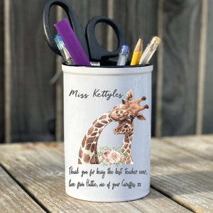 May include: White ceramic pencil holder with a giraffe design. The holder has the text "Miss Kettyles" and "Thank you for being the best teacher ever, love from Hattie, one of your Giraffes xx".