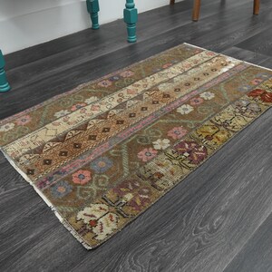 Könnte beinhalten: Ein brauner und beigefarbener Teppich mit floralen und geometrischen Mustern. Der Teppich hat einen ausgebleichten, Vintage-Look und ist aus Wolle.