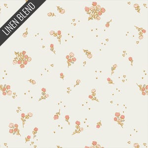 May include: Cream-colored fabric with a repeating pattern of pink and gold floral bouquets and small gold hearts. The words "LINEN BLEND" are printed diagonally in black across the upper left corner. The design is delicate and feminine.