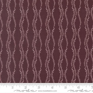 May include: A dark maroon fabric featuring a repeating vertical pattern of light pink wavy vines with small leaves. A white ruler is visible at the bottom edge, showing a scale of 7 inches, with the text "moda" and "www.modafabrics.com" printed.