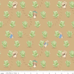 May include: Fabric with a repeating pattern featuring illustrations of rabbits, lettuce, and footprints on a tan background. The rabbits are depicted in various poses, some wearing blue jackets. Green lettuce plants are scattered throughout the design.