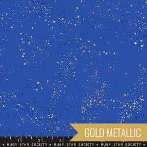May include: A blue fabric with a speckled pattern of gold, purple, and green. The fabric has the text "GOLD METALLIC" and "RUBY STAR SOCIETY" printed on it.