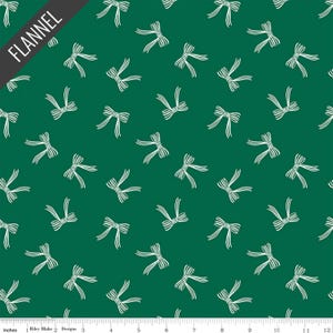 May include: Green flannel fabric with a repeating pattern of white bows. The word "FLANNEL" is printed in white on a black diagonal banner in the upper left corner. The fabric is measured in inches.