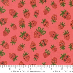 May include: A fabric with a repeating pattern of smiling strawberries on a coral background. The strawberries have green stems and leaves. The fabric is marked with a ruler at the bottom and the word "moda".