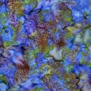 May include: A fabric swatch featuring a mottled, watercolor-style pattern in shades of blue, purple, and lime green. The surface displays a textured, organic appearance with blended color transitions and small, dark brown speckles.