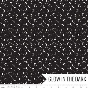 May include: Black fabric with a repeating pattern of white crescent moons and stars. The words "GLOW IN THE DARK" are in a white banner in the lower right corner. The fabric is measured in inches.