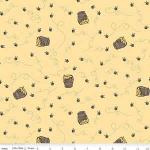 May include: A light yellow fabric with a repeating pattern of cartoon bees and beehives. The bees are black and yellow, and the beehives are brown and yellow. Dotted lines trail behind the bees, creating a whimsical design.