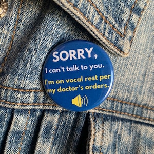 May include: A blue button with a white border and yellow text that reads "SORRY, I can't talk to you. I'm on vocal rest per my doctor's orders." A yellow speaker icon is in the lower right corner of the button.
