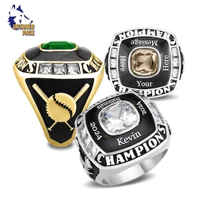 May include: Three championship rings with black enamel and silver or gold accents. One ring features a baseball design, while the others have space for personalized text. Each ring has a large central stone.
