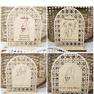 Puede incluir: Cuatro placas de madera con un diseño recortado de un arco tejido. Cada placa presenta un diseño diferente, incluyendo una mujer embarazada con flores, una mujer sosteniendo un bebé, una mujer embarazada con flores y un diseño floral con el texto "Sra. Startek". Los textos "matrona" y "su alma está hecha de flores silvestres" también están incluidos en las placas.