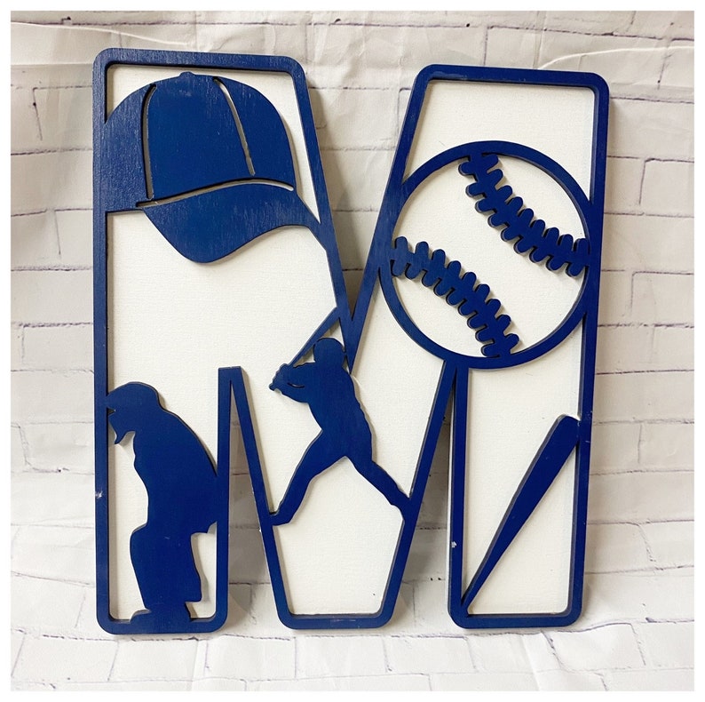 May include: Blue wooden letter M with baseball-themed cutouts. The letter features a baseball, a baseball player, a bat, and a baseball cap.