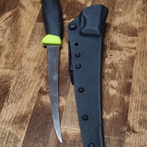 May include: A black and green fishing knife with a curved blade and a black sheath. The knife has the text "Morakniv" on the handle.