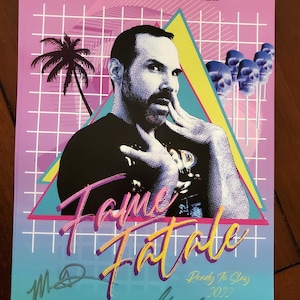 May include: A retro-style poster for the film "Fame Fatale" with a pink, blue, and yellow color scheme. The poster features a man with a beard and a skull design. The text "Ready to Slay 2022" is also on the poster.