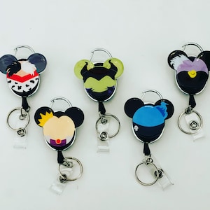Puede incluir: Cinco portagajes retráctiles con personajes de dibujos animados de villanos de Disney. Los personajes son Cruella de Vil, Maléfica, Úrsula y Hades. Los soportes son plateados con cordones retráctiles a rayas blancas y negras.