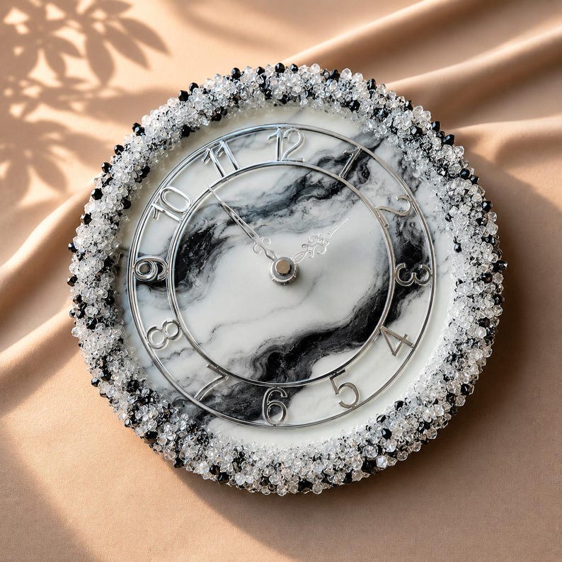 May include: A round wall clock featuring a white and black marbled face with silver-toned numerals and hands. The outer edge is heavily embellished with a dense border of small, clear and black faceted beads, creating a textured, sparkling frame.