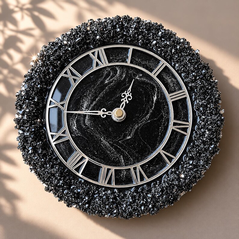 May include: A round wall clock featuring a black marbled face with silver Roman numerals and ornate silver hands. The outer border is encrusted with a thick layer of textured, sparkling black crystals, creating a high-contrast, reflective appearance.
