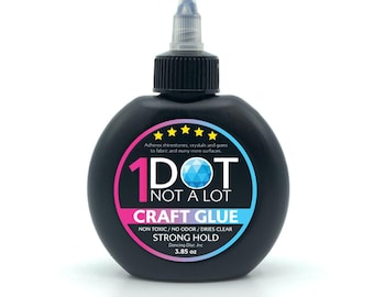 May include: A black bottle of 1 Dot Not A Lot Craft Glue with a blue and pink label. The label says "Adheres rhinestones, crystals and gems to fabric and many more surfaces." and "Non Toxic/No Odor/Dries Clear Strong Hold 3.85 oz Dancing Disc Inc."