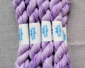 May include: Five skeins of lavender purple yarn with white speckles. The yarn is wound into balls and has a label that reads "Little Boy Bluc".