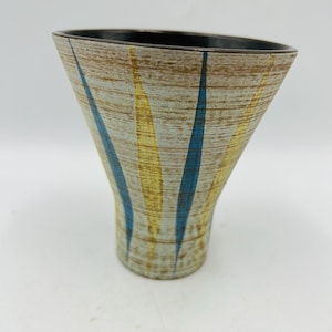 May include: A vintage ceramic vase with a flared shape. The vase features a textured, beige background with vertical stripes of blue and yellow. The rim is dark brown, and the vase has a mid-century modern aesthetic.