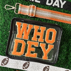 May include: Clear stadium bag with orange "WHO DEY" lettering, and several decorative straps. One strap is black with white beaded "GAME DAY" text. Other straps are orange, white, and silver with football and glitter accents.