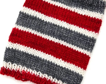 May include: A knitted fabric swatch with red, white, and gray stripes. The fabric is knit in a simple stitch.