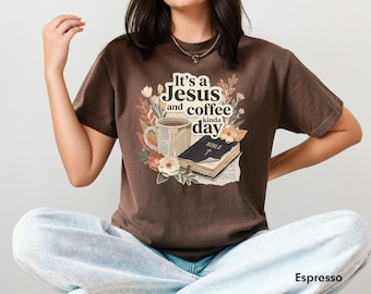 May include: A dark brown short-sleeve t-shirt featuring a graphic print of a coffee mug, an open Bible, and floral elements. The text on the shirt reads, It's a Jesus and coffee kinda day. The shirt is a solid dark brown color labeled as Espresso.