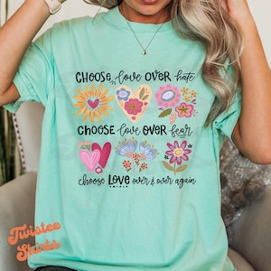 May include: A turquoise t-shirt with a floral design and the text "CHOOSE love OVER hate", "CHOOSE love OVER fear", and "choose Love over & over again".