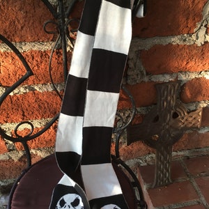 Op de afbeelding: Zwart-wit geblokte sjaal met een zwart-wit Jack Skellington gezicht aan elk uiteinde.