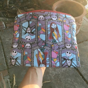 Op de afbeelding: Een kleurrijke ritszak met een glas-in-loodpatroon met Jack Skellington en Sally uit The Nightmare Before Christmas.