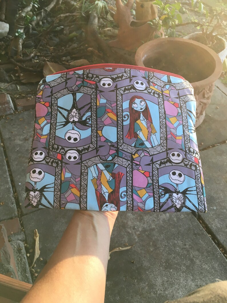 Op de afbeelding: Een kleurrijke ritszak met een glas-in-loodpatroon met Jack Skellington en Sally uit The Nightmare Before Christmas.