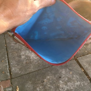 Op de afbeelding: Een rode ritszak met een blauwe voering. De zak is open en de voering is zichtbaar.