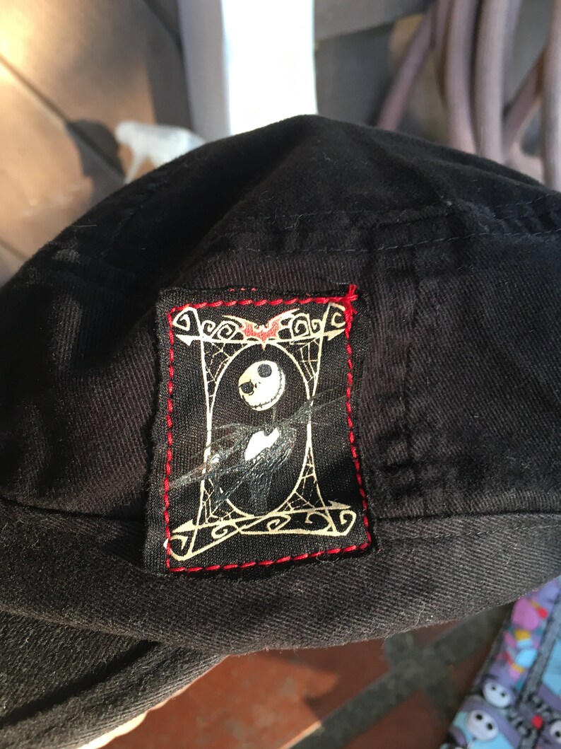 Op de afbeelding: Zwarte baseballpet met een rood gestikt patch met een witte omtrek van Jack Skellington uit The Nightmare Before Christmas.
