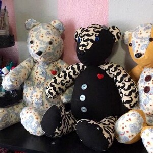 May include: Three teddy bears with different patterns and colors. The bear on the left is white with a blue and white paisley pattern. The bear in the middle is black with a white and black mustache pattern. The bear on the right is yellow with a blue and white paisley pattern.