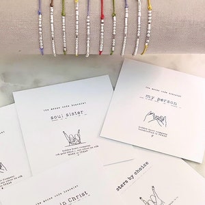 May include: A set of eight friendship bracelets with different colored strings and silver beads. Each bracelet has a different message on it, including "soul sister", "bff", "my person", "sisters in Christ", and "sisters by choice".