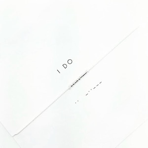 Peut inclure: Une carte blanche avec les mots "I DO" écrits en noir. En dessous, une représentation en code Morse de la même phrase. La carte a un bord déchiré et une surface blanche texturée.