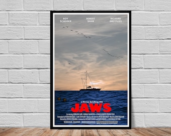 May include: A vintage movie poster for the film Jaws, featuring a boat on the ocean with a flock of birds flying overhead. The poster is in a black frame and has the title "JAWS" in red letters. The poster also includes the names of the actors Roy Scheider, Robert Shaw, and Richard Dreyfuss.