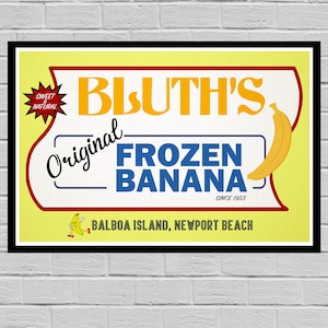 May include: A yellow and red sign with the text "Bluth's Original Frozen Banana" in blue and white lettering. The sign also includes the text "Sweet & Natural" in a red starburst and "Since 1953" in small white text. The sign also includes a cartoon banana with legs and arms and the text "Balboa Island, Newport Beach".