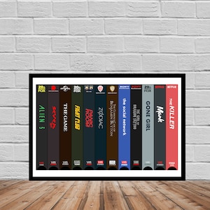 May include: A framed print of a collection of VHS tapes, each with a different movie title. The titles include "Alien 3", "Seven", "The Game", "Fight Club", "Panic Room", "Zodiac", "The Curious Case of Benjamin Button", "The Social Network", "The Girl with the Dragon Tattoo", "Gone Girl", "Mank", and "The Killer".