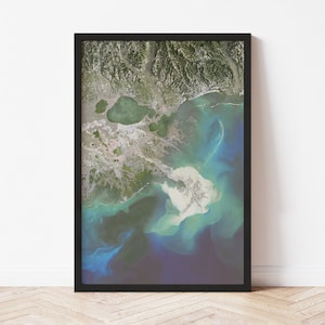 May include: An aerial photograph of a river delta with a large body of water in the background. The water is a deep blue color and the delta is a mix of green and brown. The image is taken from a high angle and shows the intricate details of the delta.