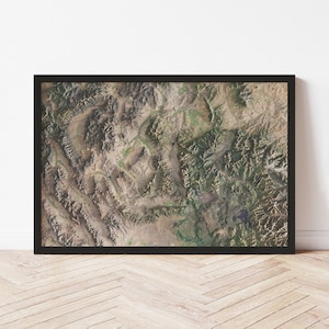 May include: An aerial photograph of a mountainous region with a variety of green and brown hues. The image shows a rugged landscape with deep valleys and high peaks.