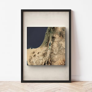 May include: A framed print of a topographical map of Israel, showing the country's terrain and the Dead Sea. The map is printed in shades of brown, green, and blue, and is framed in a black frame.