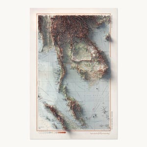 May include: A vertical relief map print of Southeast Asia featuring a light blue ocean background and dark brown, textured mountain ranges. The map includes grid lines, geographical labels, and a color-coded elevation scale at the bottom.