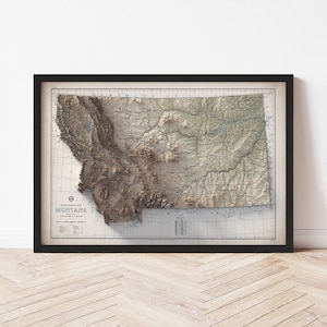 May include: Framed vintage map of Montana, featuring a detailed relief of the state's topography. The map is in shades of brown, beige, and green, with the state name prominently displayed. The map is encased in a black frame.