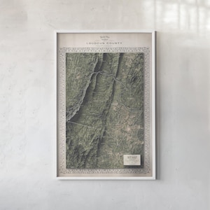 May include: A framed topographical map of Loudoun County featuring dark green terrain, mountain ridges, and winding roads. The print includes a decorative border, the text 'Loudoun County' at the top, and a small rectangular 'Atlas' label at the bottom.