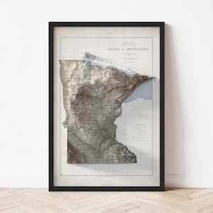May include: Framed vintage map of Minnesota, USA, with a 3D topographic effect. The map is in a black frame and features the state's outline, major cities, and geographical features. The text "STATE OF MINNESOTA" is visible.